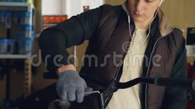 年轻男子专业维修人员用艾伦键和握持固定自行车车把的耳机拍摄下来
